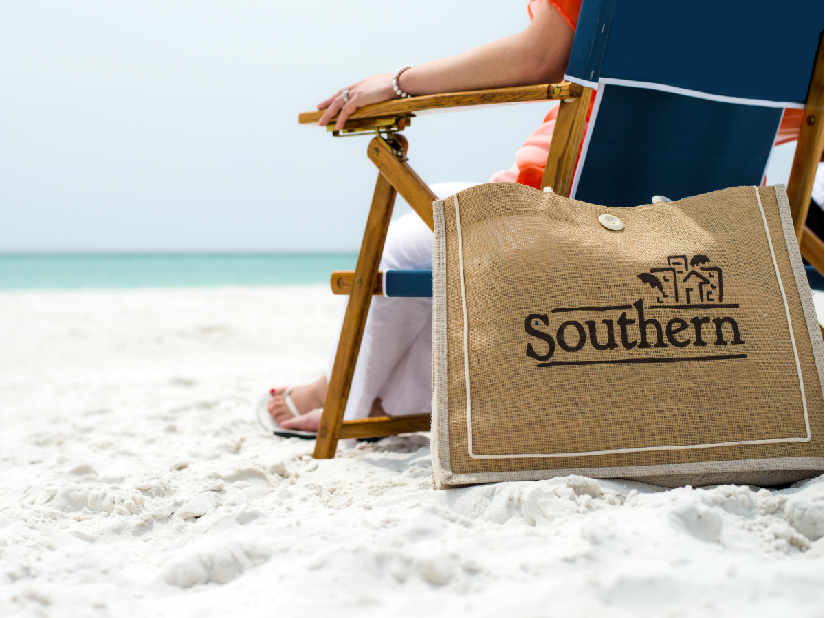 Person sitting on the beach with Southern beach bag.